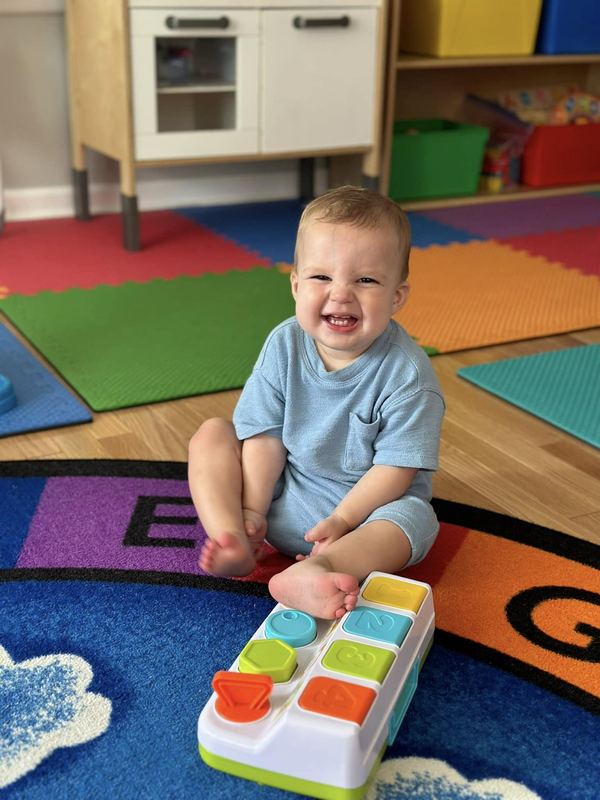 A smiling baby with a pop-up toy