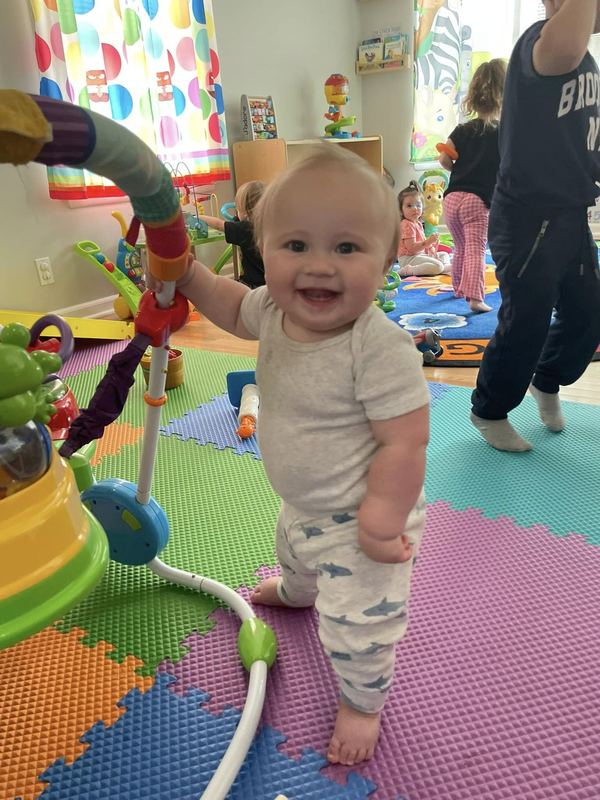A smiling baby standing up on the play mats