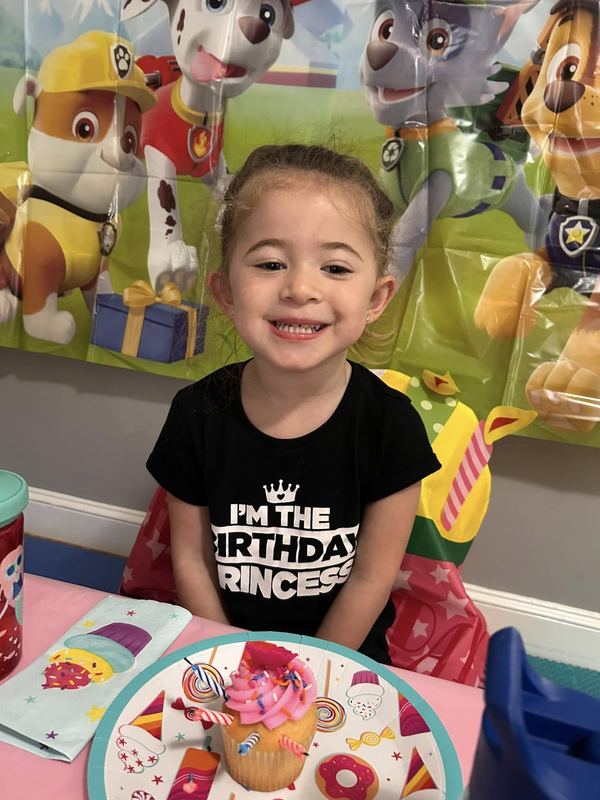 A smiling birthday girl with her cupcake