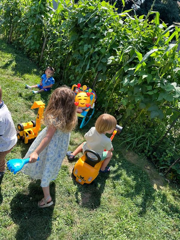 Children with ride-on toys beside the garden