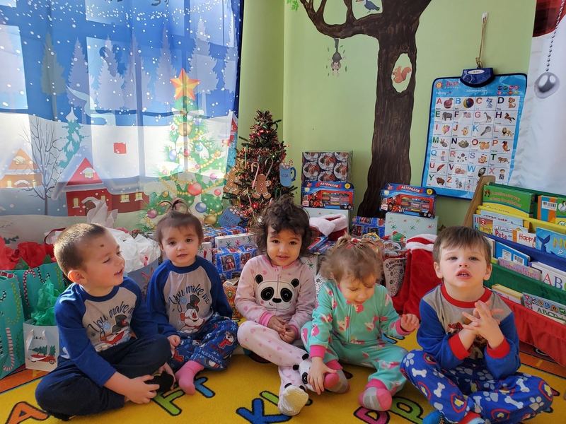 Toddlers in pajamas sitting together on the alphabet rug