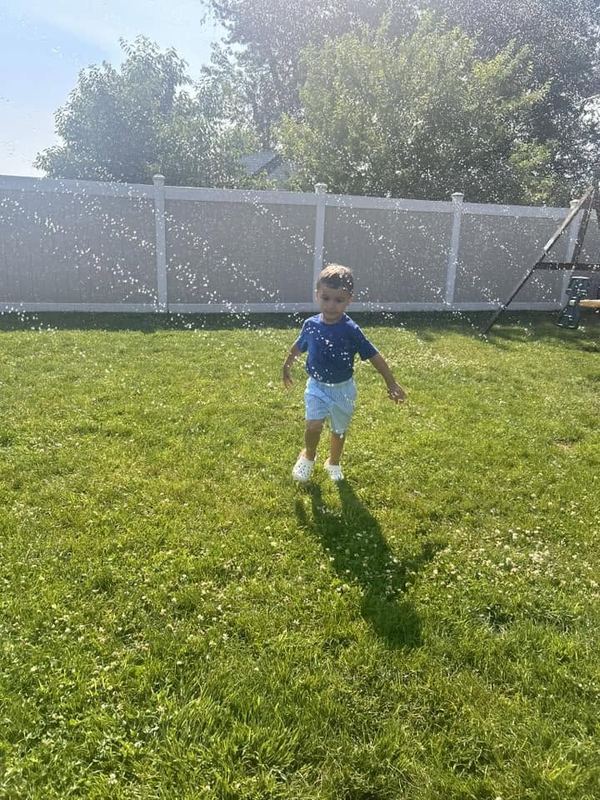 A toddler walking across the sunny lawn