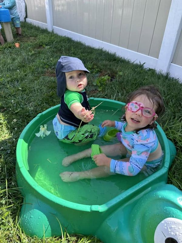 Two toddlers splashing in the turtle sandbox