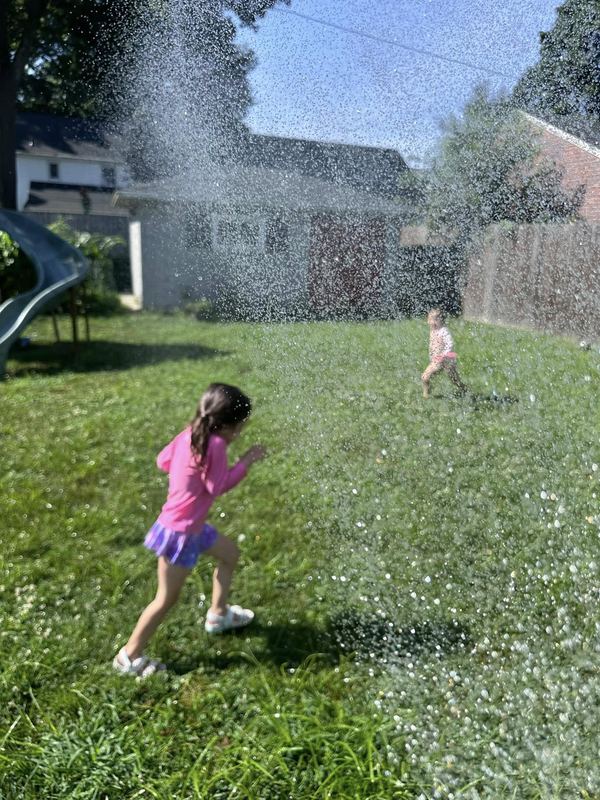A girl running through the sprinkler