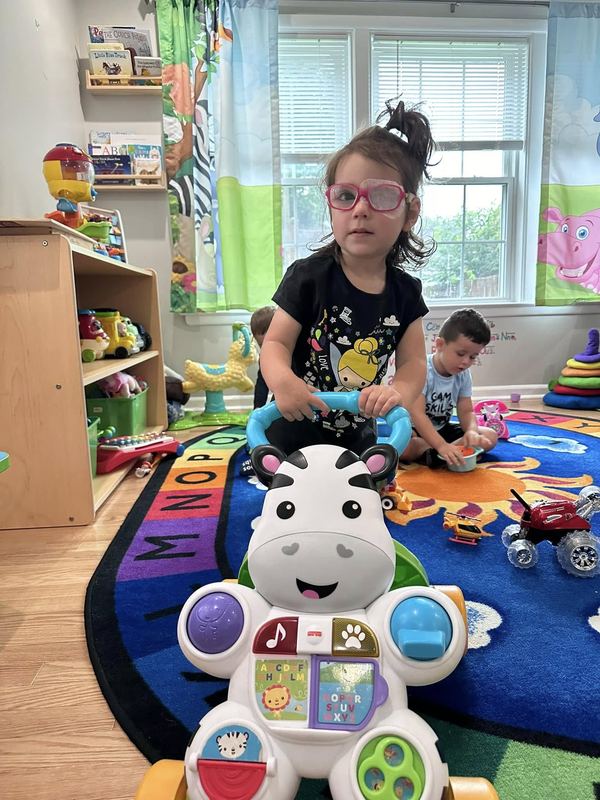 A girl in glasses playing with a zebra toy